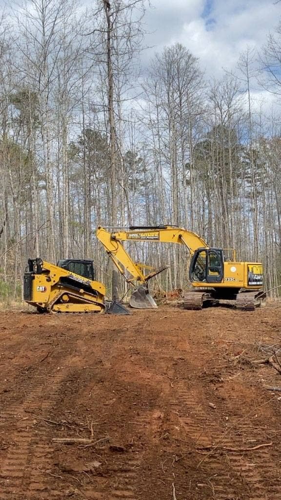 Two pieces of equipment on a red clay jobsite