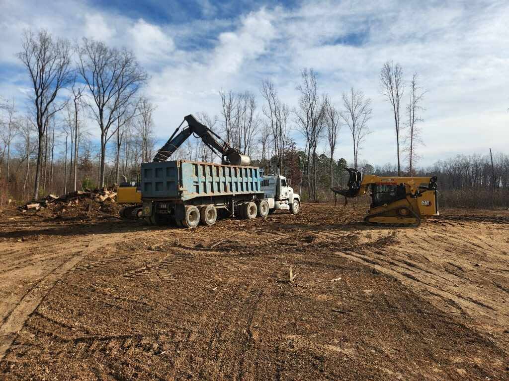 Excavator and compact track loader loading a dump truck during site cleanup